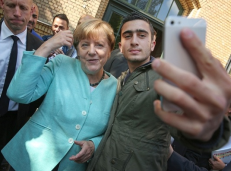 Karo pabėgėlis įsiamžina su Vokietijos kanclere. Nuotr. thetimes.co.uk