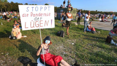 Moteris proteste Miuchene (Vokietija) su plakatu, ant kurio vokiškai užrašyta: "Sustabdykite melo pandemiją". dw.com nuotr.